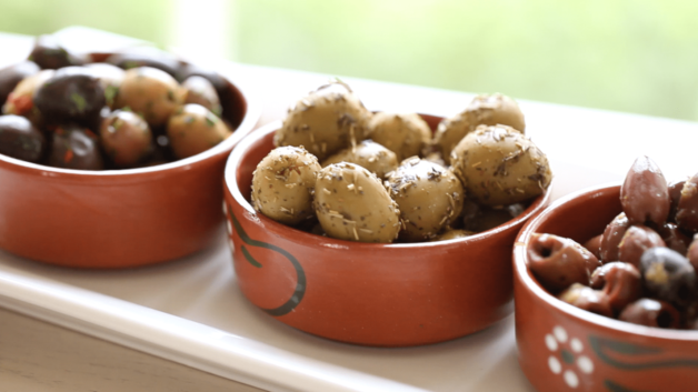 Olives in terra cotta dishes on a white rectangular platter