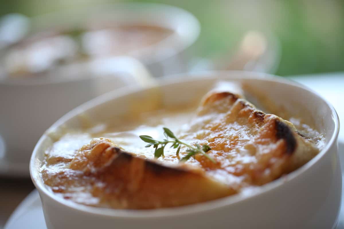 French Onion Soup in a white Bowl with a Garnish of Thyme