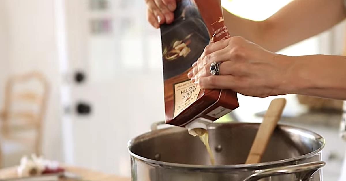 adding Beef Broth to a large soup pot