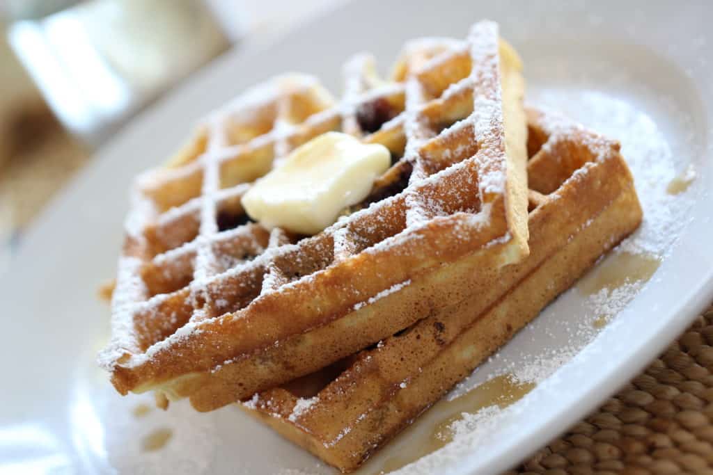 Blueberry Waffle Recipe served on a white plate with a pat of butter and syrup on the waffles