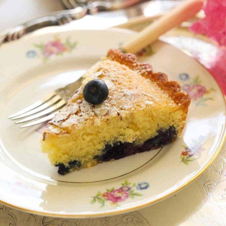 a slice of blueberry almond cake on a floral plate with fork