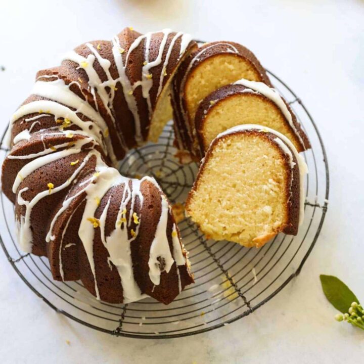 A lemon pound cake sliced and glazed on a cooling rack