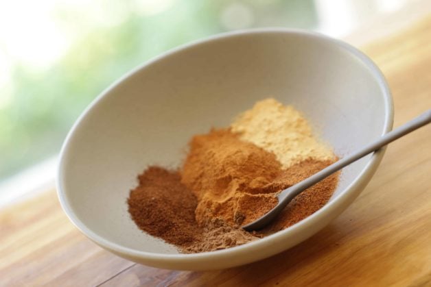 A bowl of spices in a gray bowl with a spoon 