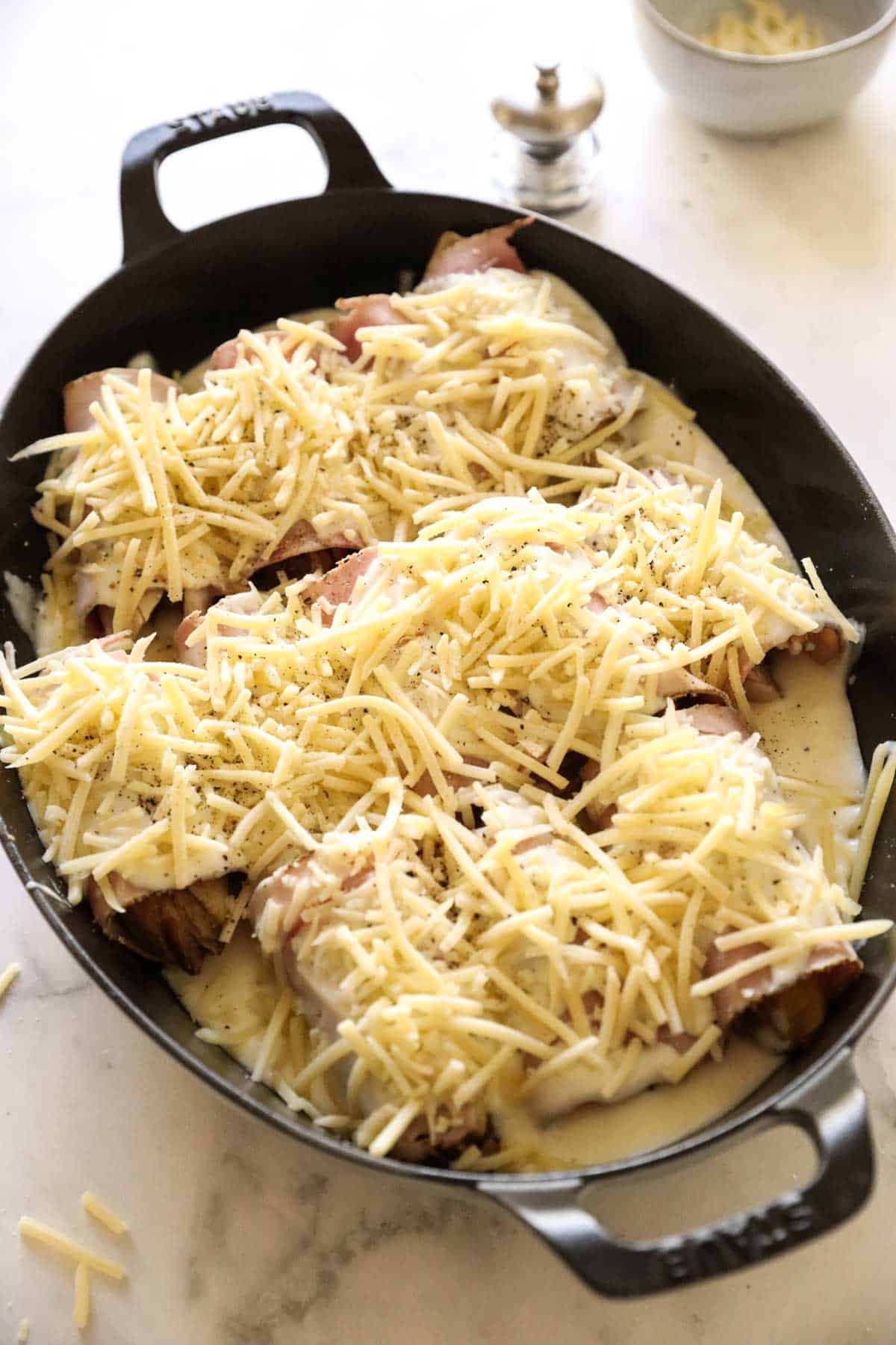 a gratin dish filled with endive rolled in ham and topped with cheese