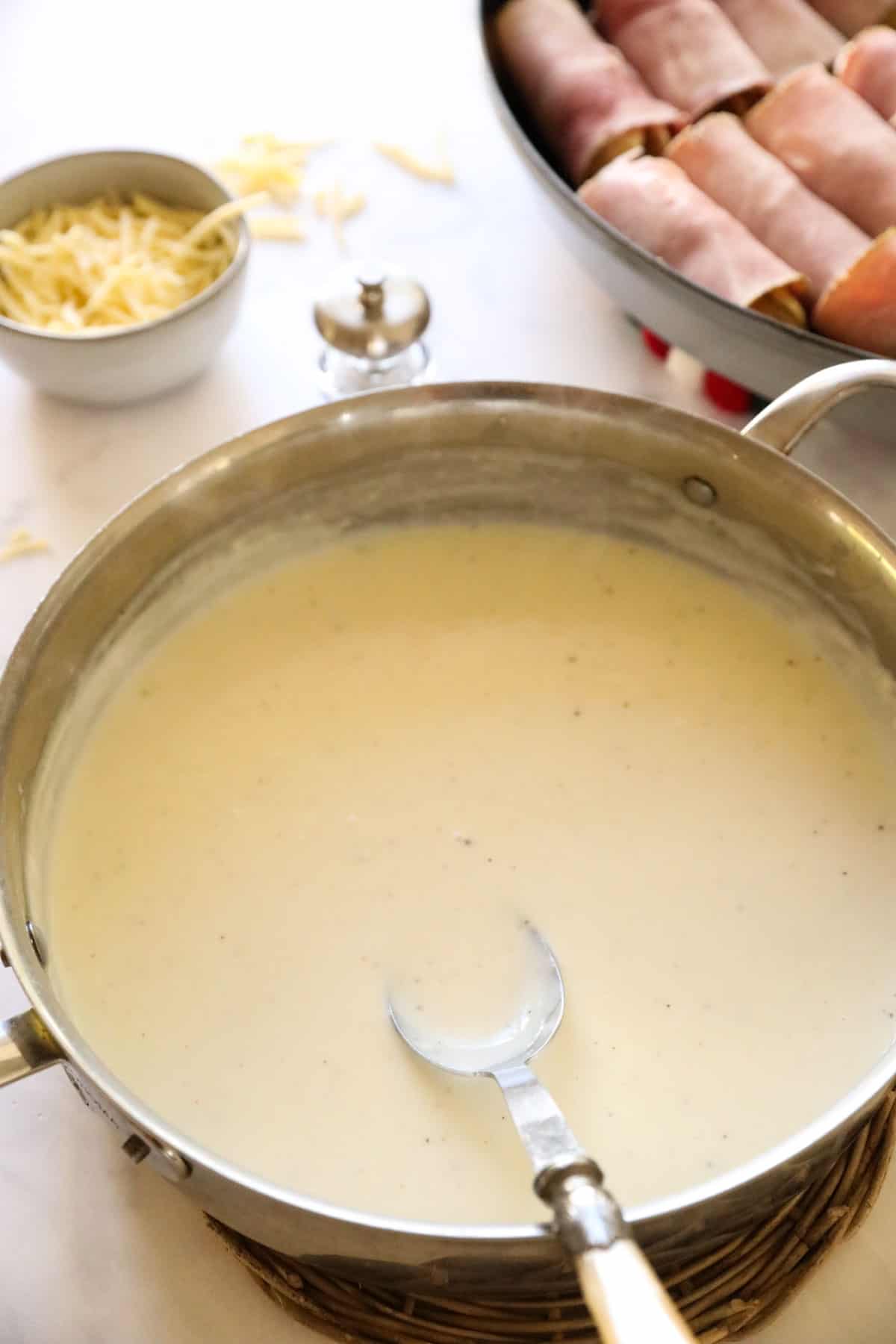 bechamel sauce in a skillet with a sppon