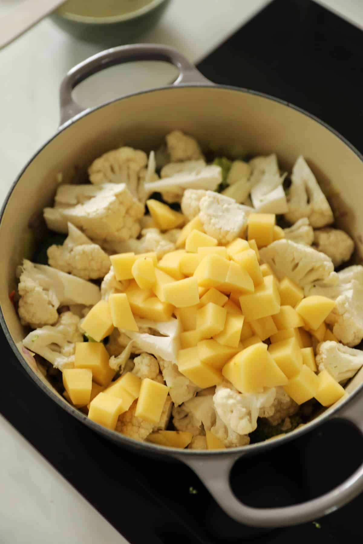 A soup pot filled with vegetables on a cooktop.