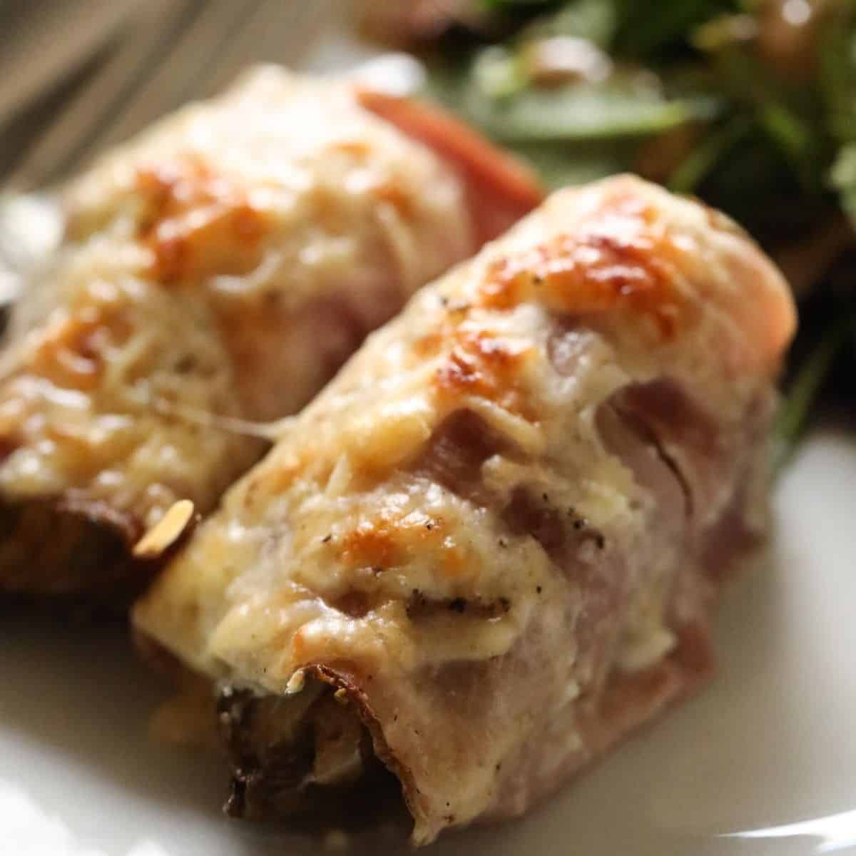 a serviong of two endive wrapped with ham and cheese