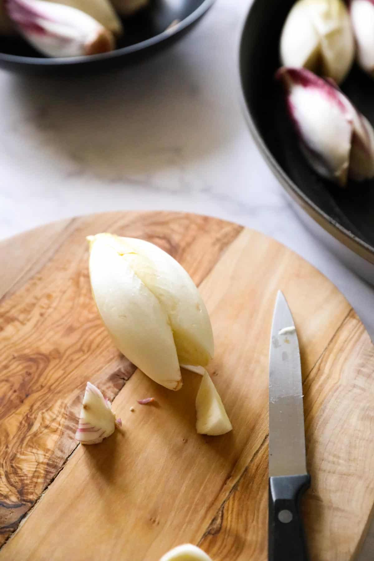 an endive on a cutting board with its core sliced out