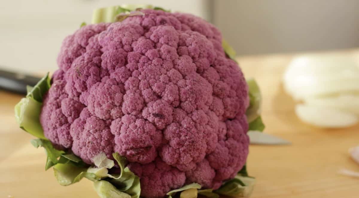 a head of purple cauliflower on a cutting board