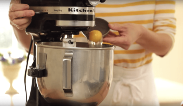 An egg is added to a black Kitchen Aid mixer
