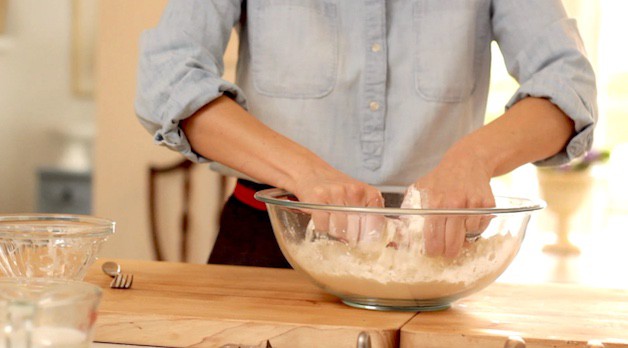 mixing biscuit dough with hands in a large glass bowl