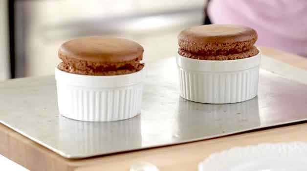 2 highly risen baked chocolate souffles on baking sheet