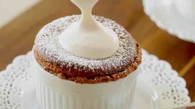 adding pourable whipped cream to the top of a chocolate souffle
