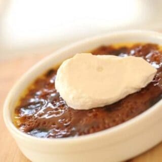 A Crème brûlée served in a white ramekin topped with whipped cream