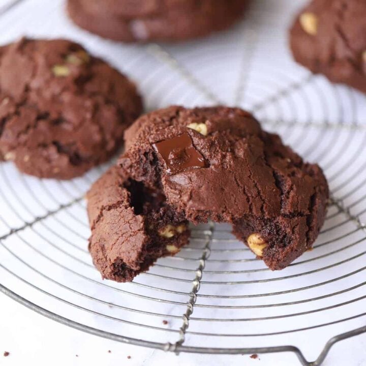 a double chocolate cookie with a bit taken out on a cooling rack