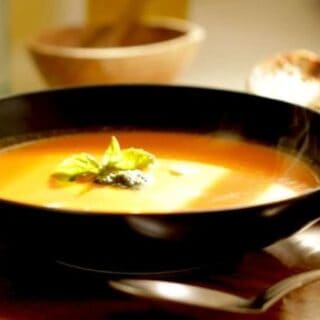 easy tomato soup recipe served in a large black bowl with fresh basil on top