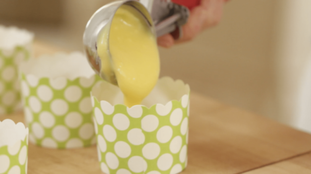 pie filling being added to green cupcake liners on a wood surface