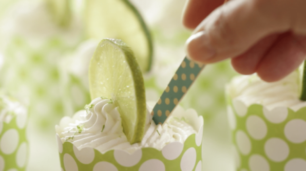 a person holding a blue wooden spoon in a key lime cup