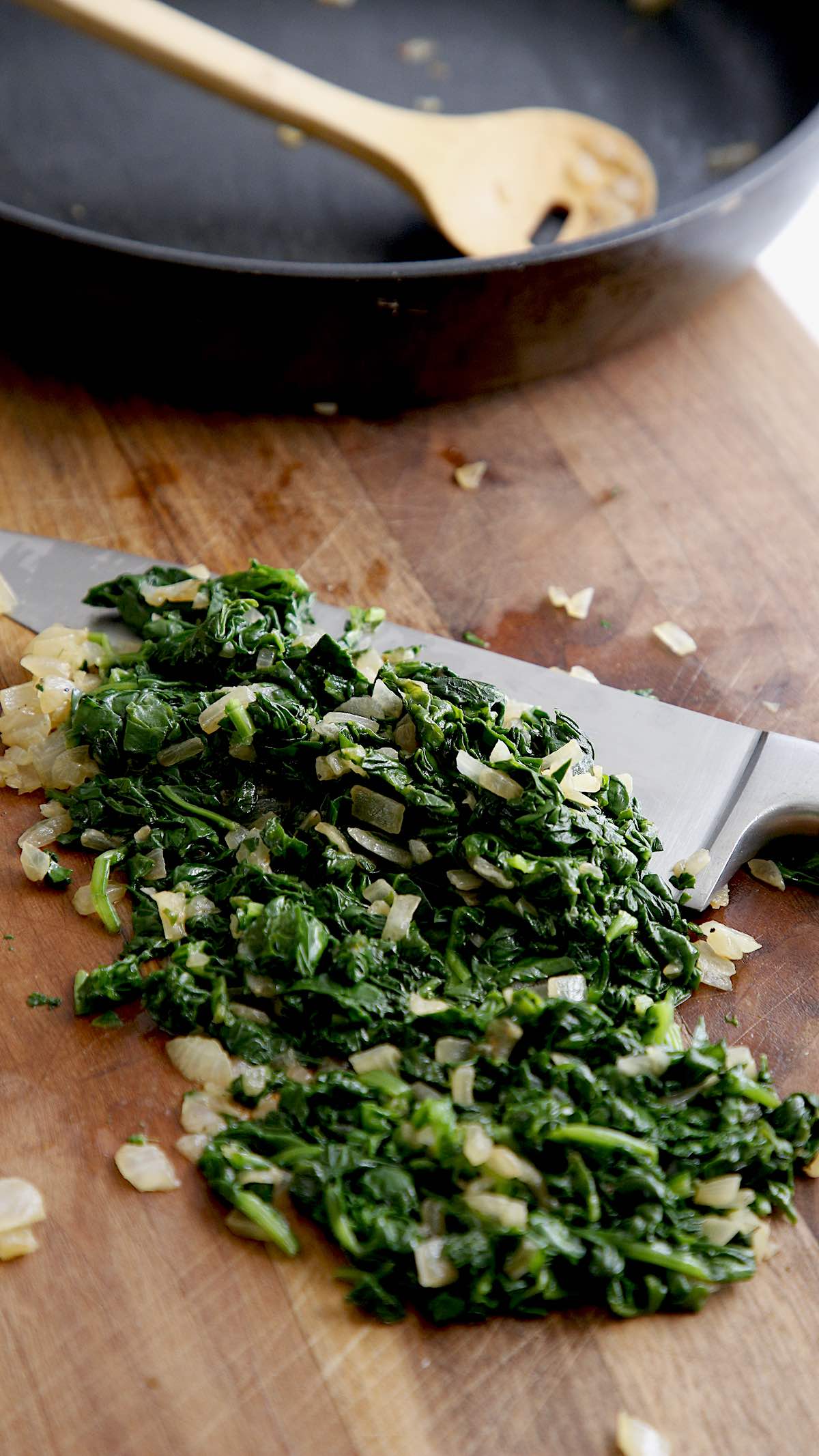 Cooked Spinach on a Cutting Board, chopped with onions and a knife