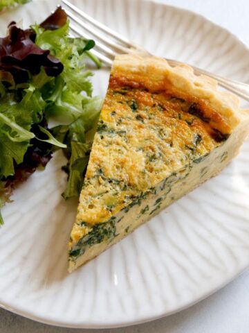 Slice of Spinach Quiche on a Plate with Salad
