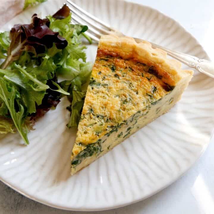 Slice of Spinach Quiche on a Plate with Salad