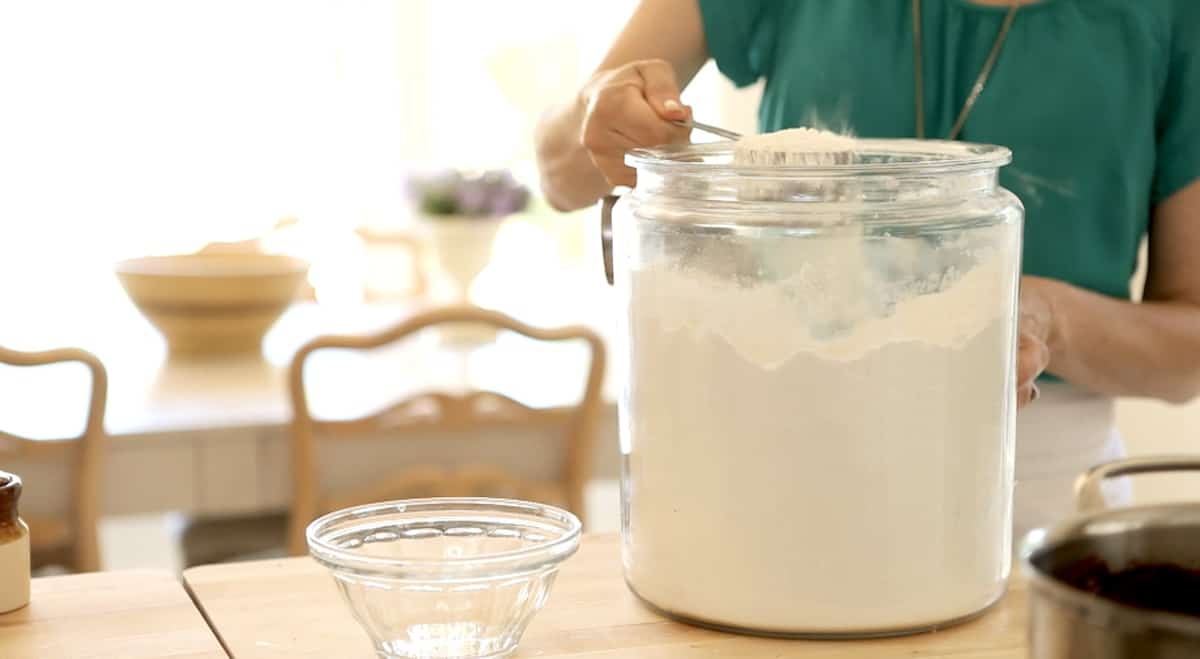 Measuring out flour from a canister into a measuring cup