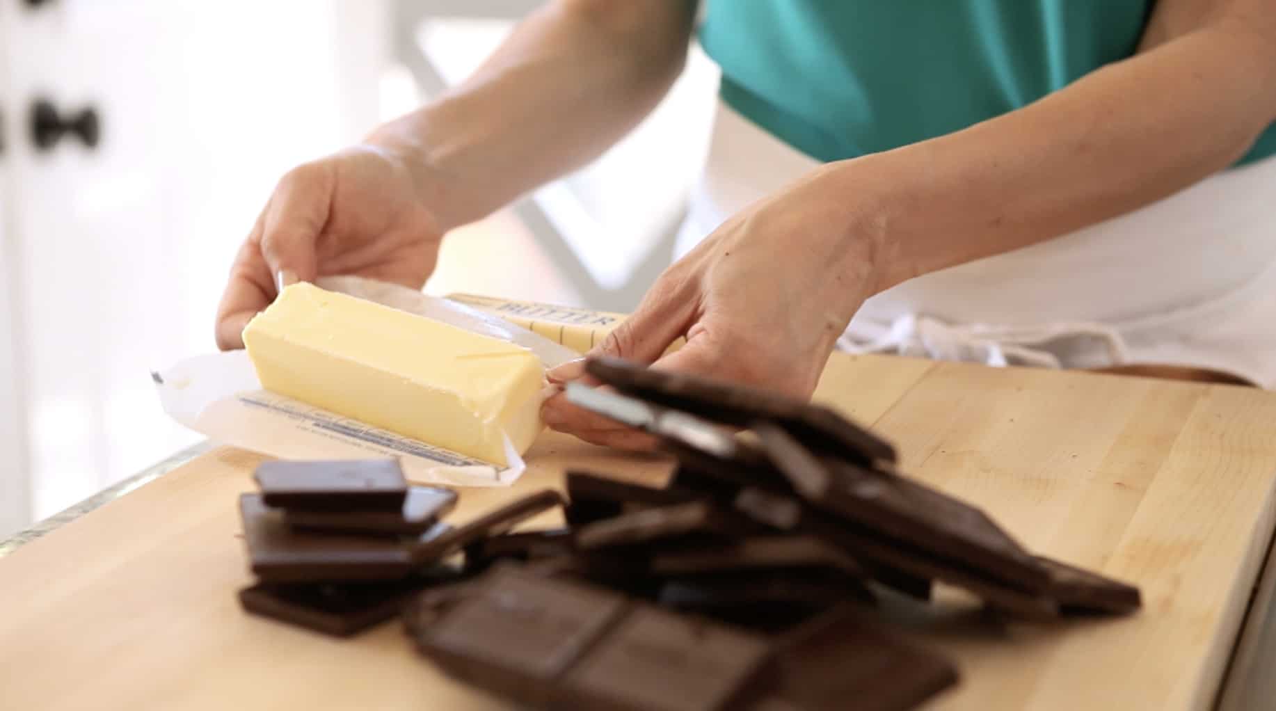 A person unwraping butter sticks with chocolate in the foreground