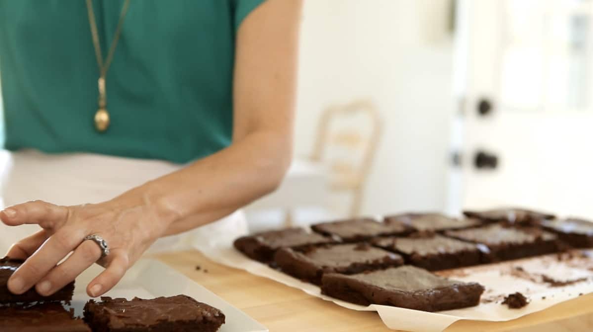 a person cutting brownies that were baked in parchment paper