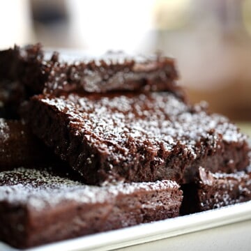 a platter of fudgy brownies dusted with powdered sugar