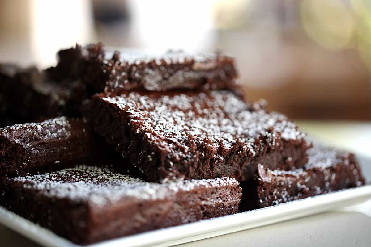 a platter of fudgy brownies dusted with powdered sugar
