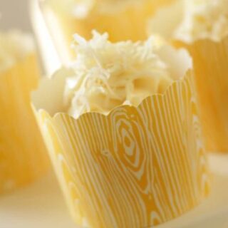 Banana Coconut Cupcake served in a yellow paper cup on a white cake stand