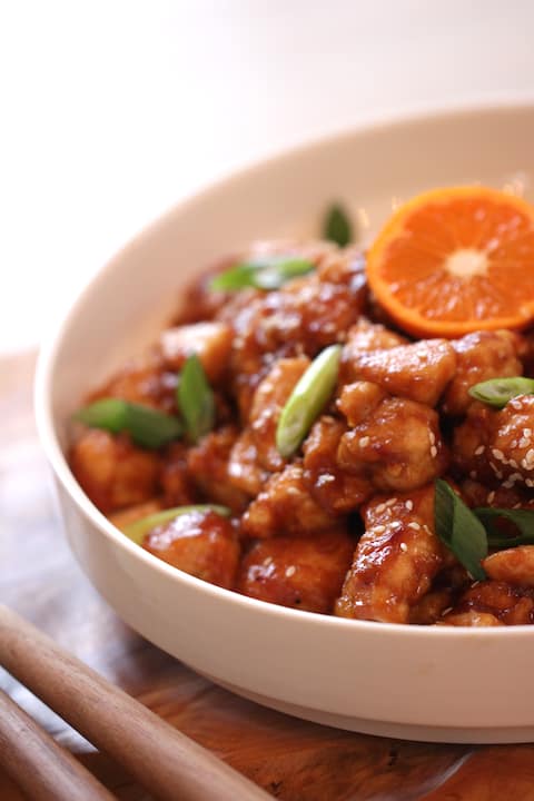 How to Make Orange Chicken recipe served in a white bowl garnished with citrus