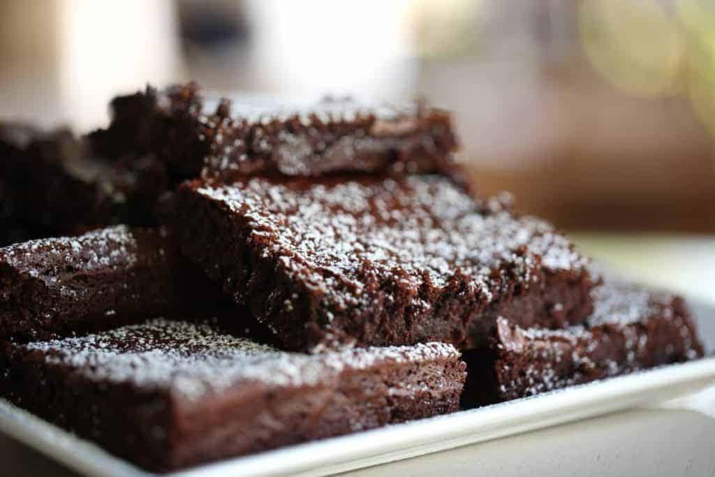 Fudgy Brownies cut into squares and stacked on a white platter