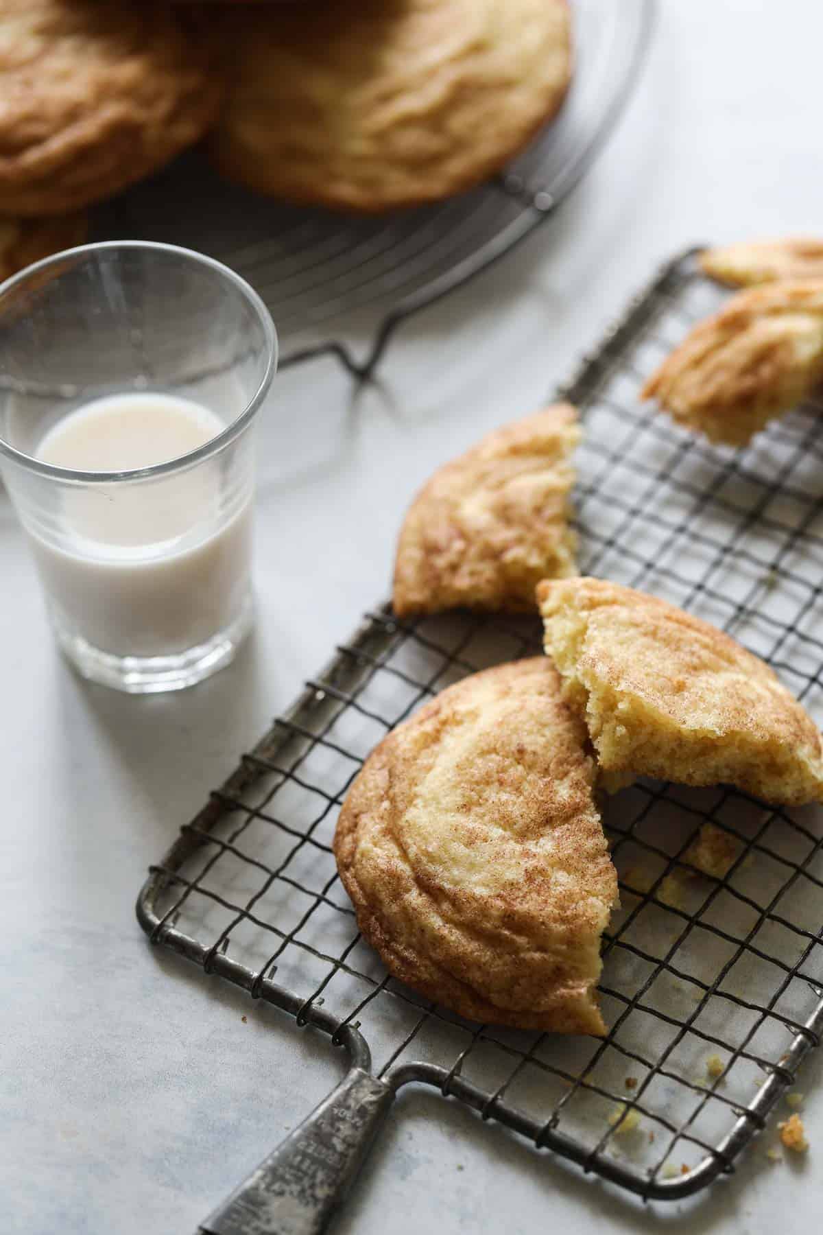 snickerdoodle cookies broken apart on a cooling rack with a glass of milk
