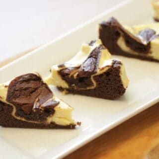 Cream Cheese Brownies sliced into triangles served on a white rectangular platter