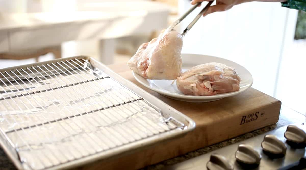 adding chicken breasts to a sheet pan with a rack