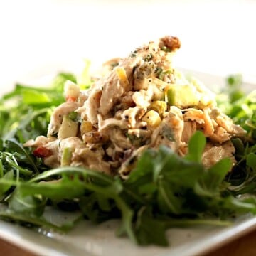 a mound of chicken salad on a bed of greens