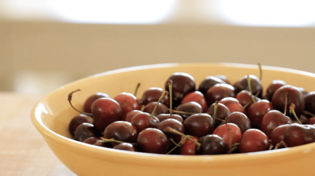 cherries in a beige bowl waiting to be pitted