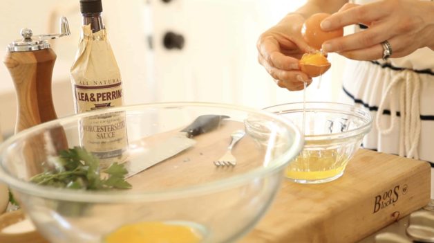 hand separating egg yolks from egg whites into a clear bowl 