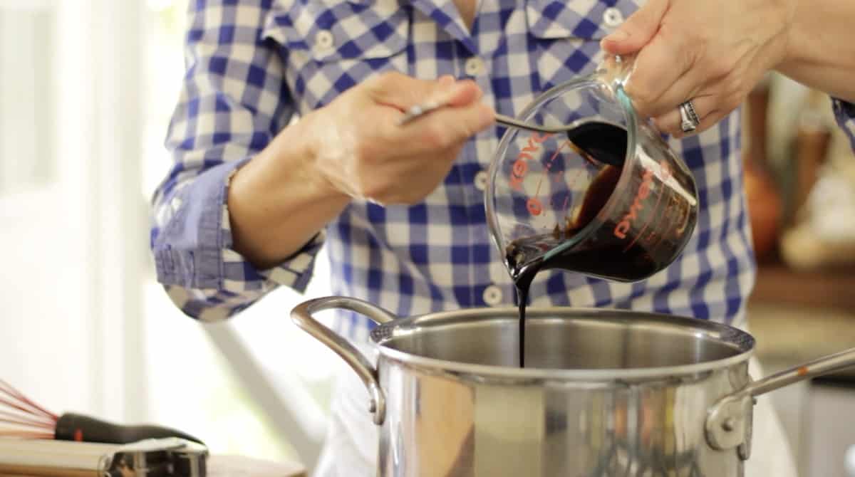 a person pouring Molasses into a pot from a measuring pitcher