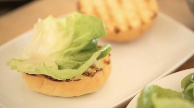 bibb lettuce on top of a toasted brioche bun on a white plate 