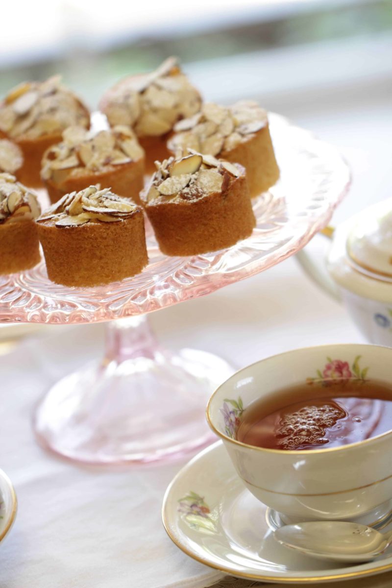 Raspberry Almond Thimble Cakes served on a cake stand with a cup of tea