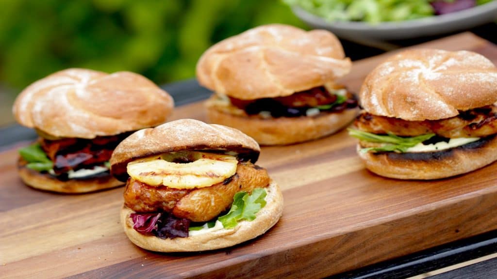 Grilled Teriyaki Chicken Sandwiches with Pineapple on a cutting board outside