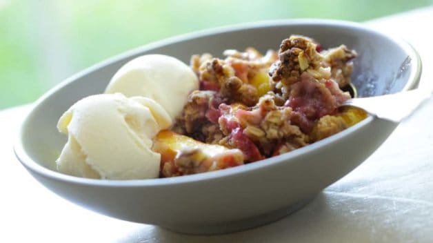 summer fruits crumble recipe served in a large bowl with vanilla ice cream