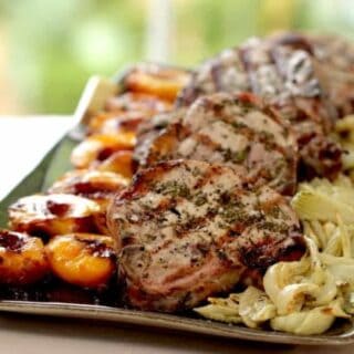 pork chops served on a large platter with grilled nectarines and roasted fennel