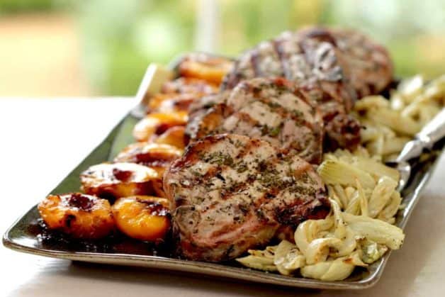 pork chops served on a large platter with grilled nectarines and roasted fennel