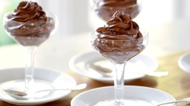 3 glas chokolademousse på et bord, der hviler på tallerkener i champagne coupe