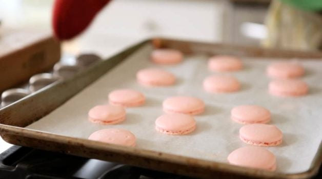 Pink Macaron shell coming out of the oven on a baking tray