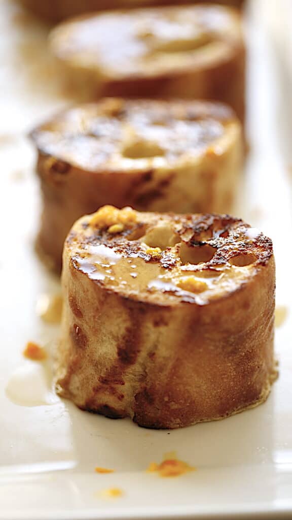 a vertical shot of 3 pain perdu slices on a white plate
