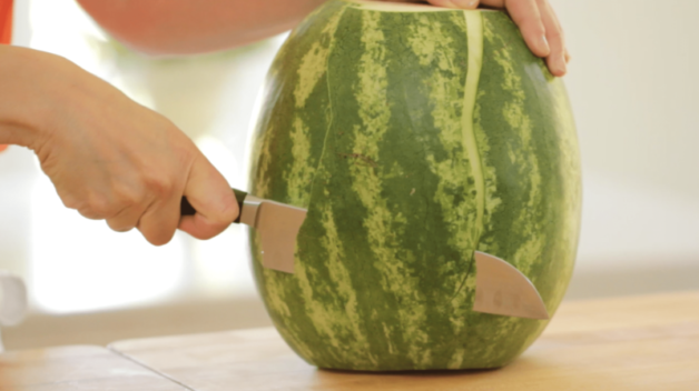 How to Make Watermelon Lemonade using a large knife to slice the green skin off of the watermelon